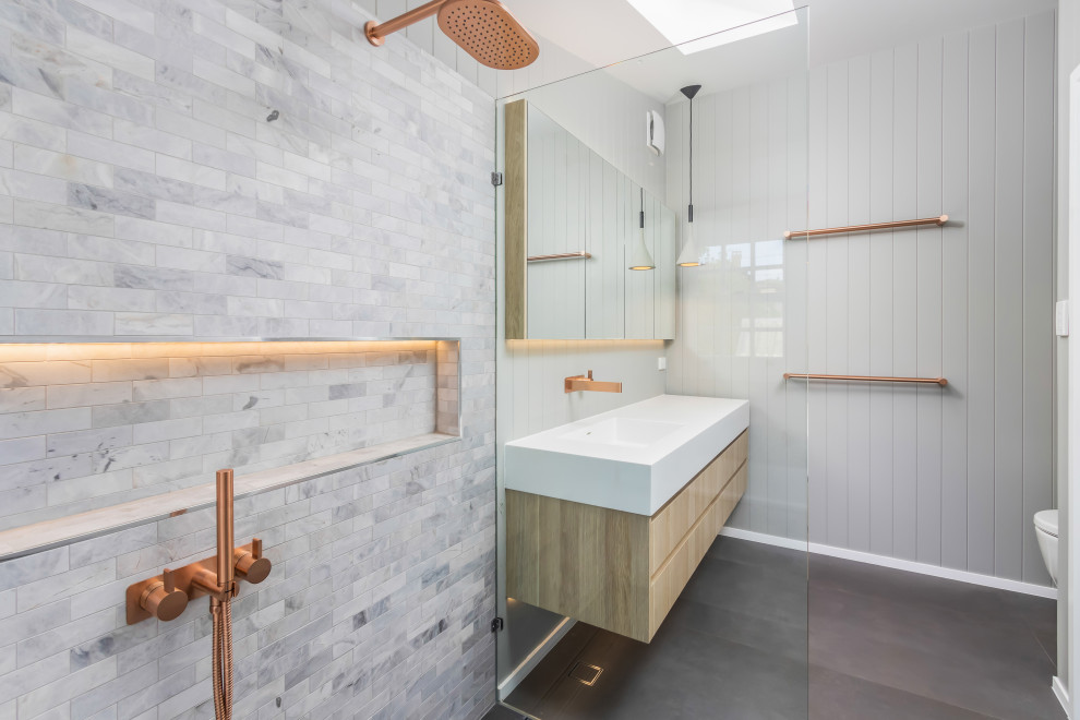 Inspiration för mellanstora moderna vitt en-suite badrum, med möbel-liknande, skåp i ljust trä, ett platsbyggt badkar, våtrum, en toalettstol med hel cisternkåpa, tunnelbanekakel, klinkergolv i porslin, ett integrerad handfat, bänkskiva i akrylsten, grått golv och med dusch som är öppen