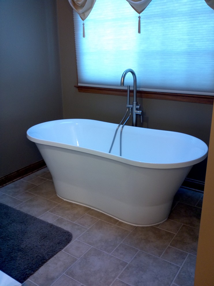 Imagen de cuarto de baño tradicional renovado de tamaño medio con bañera exenta, paredes grises y suelo de travertino
