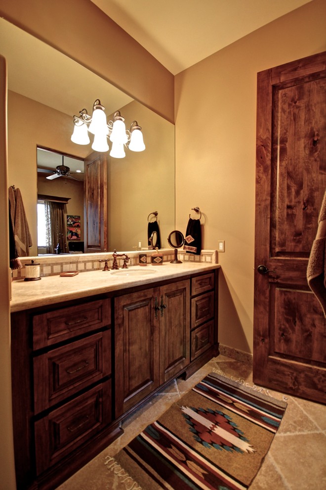 Example of a mid-sized southwest travertine floor bathroom design in Phoenix with raised-panel cabinets, dark wood cabinets, beige walls, an undermount sink and granite countertops