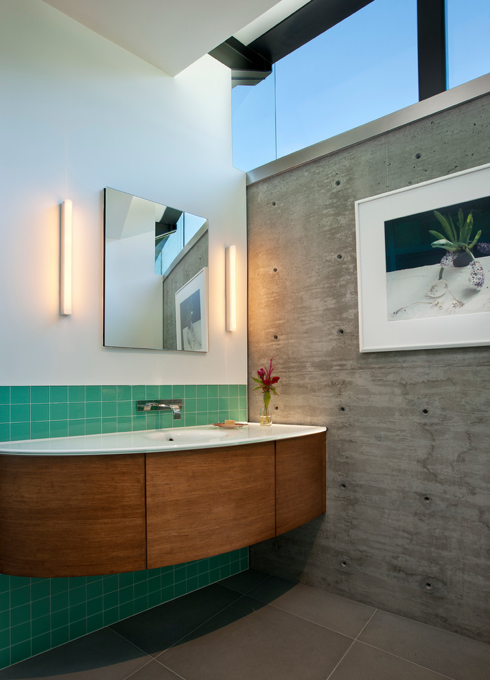 Inspiration pour une salle de bain design en bois brun avec un placard à porte plane, un carrelage vert, des carreaux de céramique, un mur blanc, carreaux de ciment au sol, un lavabo intégré et un plan de toilette en verre.