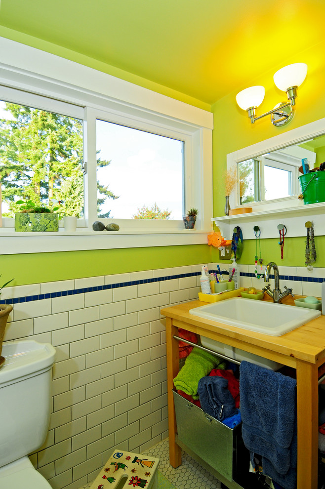 Свежая идея для дизайна: детская ванная комната в стиле кантри с накладной раковиной, открытыми фасадами, светлыми деревянными фасадами, столешницей из дерева, ванной в нише, душем над ванной, раздельным унитазом, белой плиткой, керамической плиткой, зелеными стенами и полом из керамической плитки - отличное фото интерьера