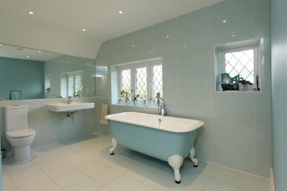 This is an example of a medium sized contemporary bathroom in London with a claw-foot bath, a one-piece toilet, blue tiles, blue walls and white floors.