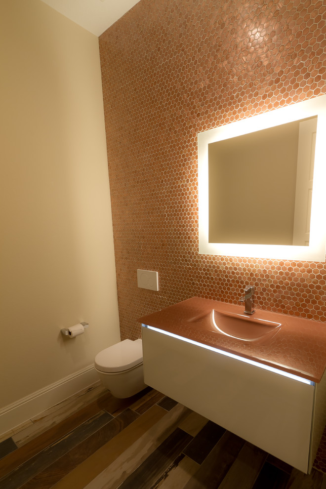 На фото: маленькая ванная комната в стиле модернизм с фасадами островного типа, белыми фасадами, инсталляцией, оранжевой плиткой, стеклянной плиткой, бежевыми стенами, полом из керамогранита, монолитной раковиной и столешницей из искусственного камня для на участке и в саду с