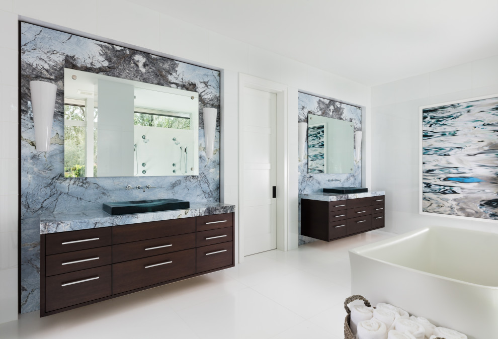 Modernes Badezimmer En Suite mit flächenbündigen Schrankfronten, dunklen Holzschränken, freistehender Badewanne, weißer Wandfarbe, Aufsatzwaschbecken, weißem Boden, blauer Waschtischplatte, Doppelwaschbecken und schwebendem Waschtisch in Tampa