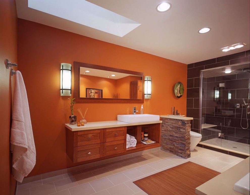 Exemple d'une grande douche en alcôve principale tendance en bois brun avec un placard à porte shaker, une baignoire posée, WC à poser, un carrelage noir, un carrelage gris, des carreaux de porcelaine, un mur orange, un sol en carrelage de porcelaine, une vasque et un plan de toilette en quartz modifié.