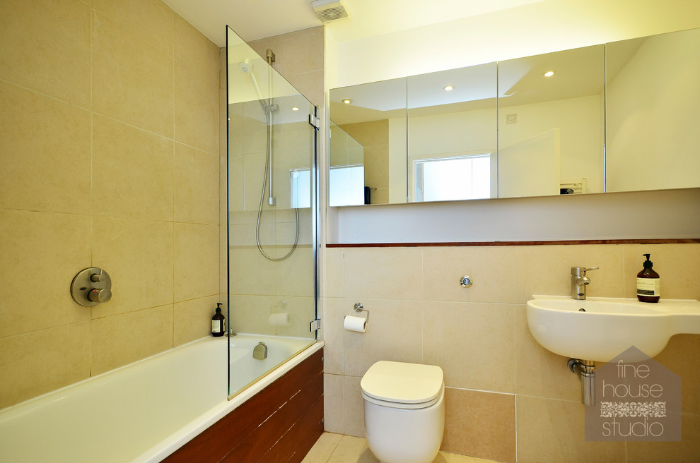 Immagine di una piccola stanza da bagno con doccia moderna con lavabo sospeso, ante lisce, top in legno, vasca sottopiano, WC sospeso, piastrelle beige, piastrelle in ceramica e pareti bianche