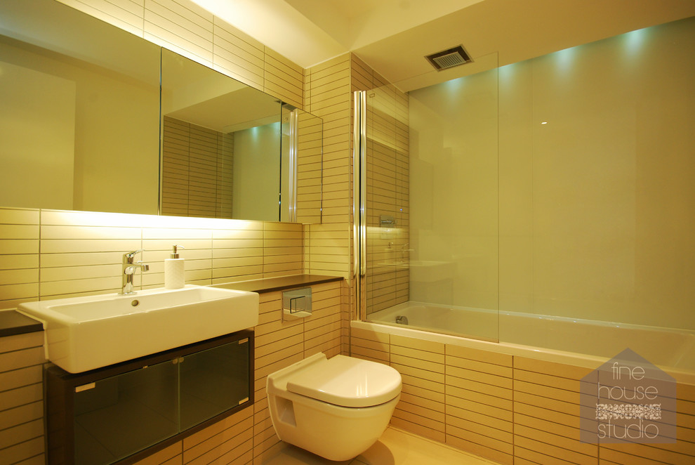 Modern inredning av ett litet badrum med dusch, med ett väggmonterat handfat, släta luckor, en hörndusch, en toalettstol med hel cisternkåpa, beige kakel, keramikplattor och vita väggar