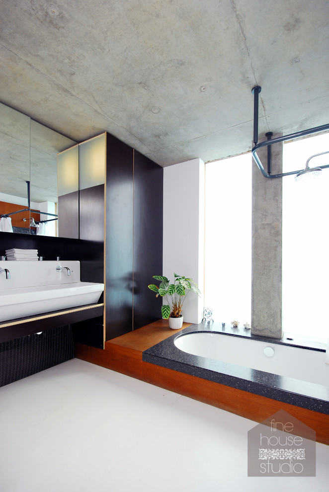 Foto de cuarto de baño principal de estilo zen grande con lavabo sobreencimera, armarios tipo mueble, puertas de armario negras, bañera encastrada, sanitario de una pieza, paredes blancas y suelo de cemento
