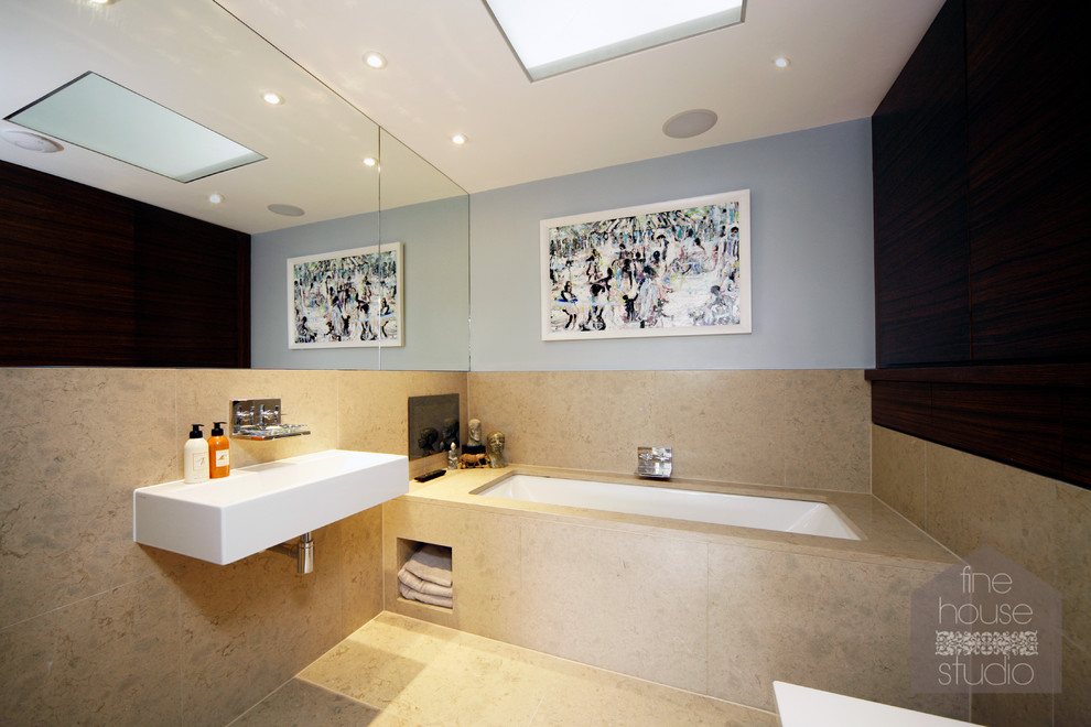 Immagine di una grande stanza da bagno padronale minimal con lavabo sospeso, top in quarzo composito, vasca sottopiano, WC monopezzo, piastrelle beige, piastrelle in pietra, pareti grigie e pavimento in travertino