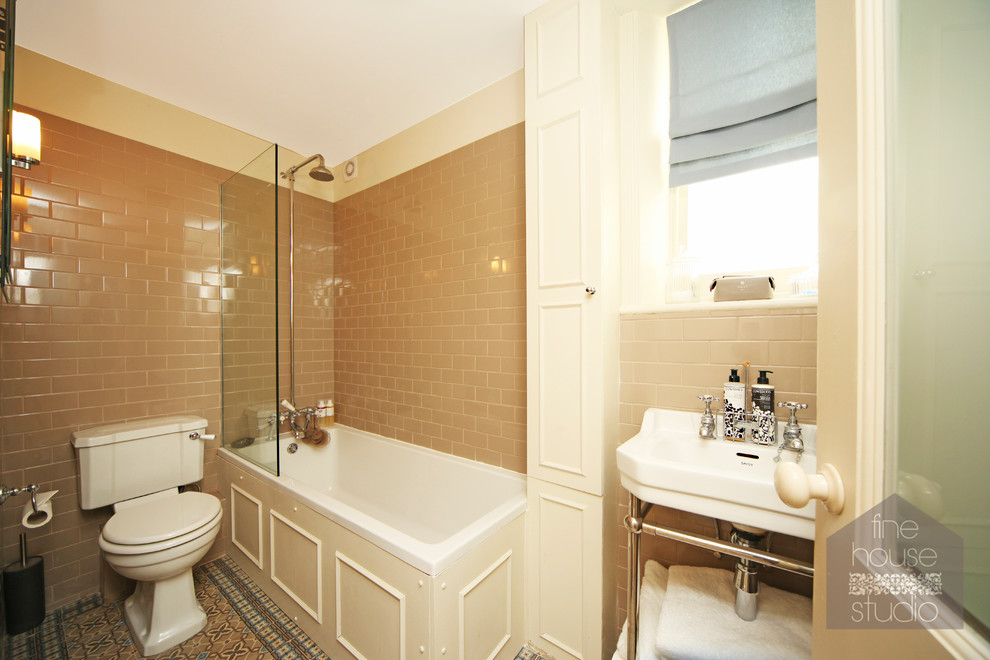 Kleines Klassisches Duschbad mit Waschtischkonsole, Unterbauwanne, Duschbadewanne, Wandtoilette mit Spülkasten, beigen Fliesen, Keramikfliesen, beiger Wandfarbe und Mosaik-Bodenfliesen in Gloucestershire