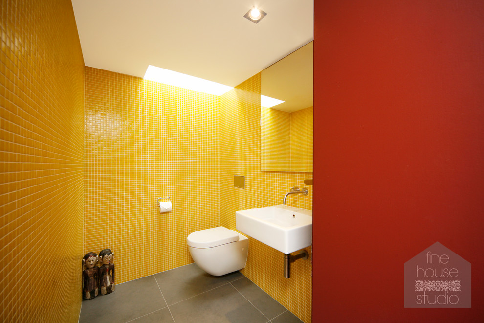 Foto på ett mellanstort funkis badrum med dusch, med ett väggmonterat handfat, släta luckor, en vägghängd toalettstol, gul kakel, keramikplattor, röda väggar och travertin golv