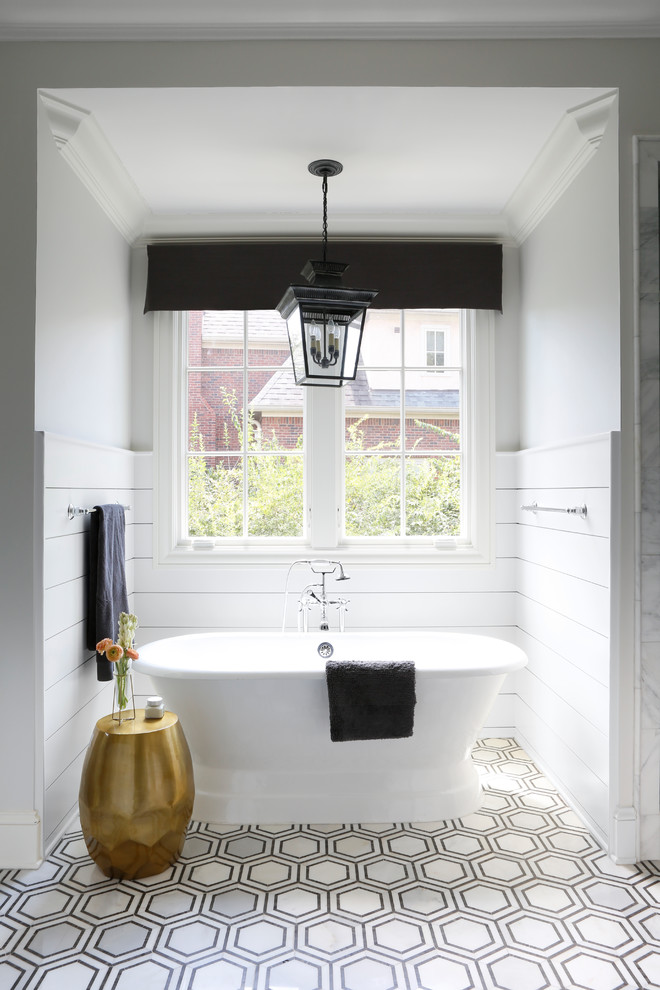 Immagine di una stanza da bagno classica con vasca freestanding, pareti bianche e pavimento multicolore