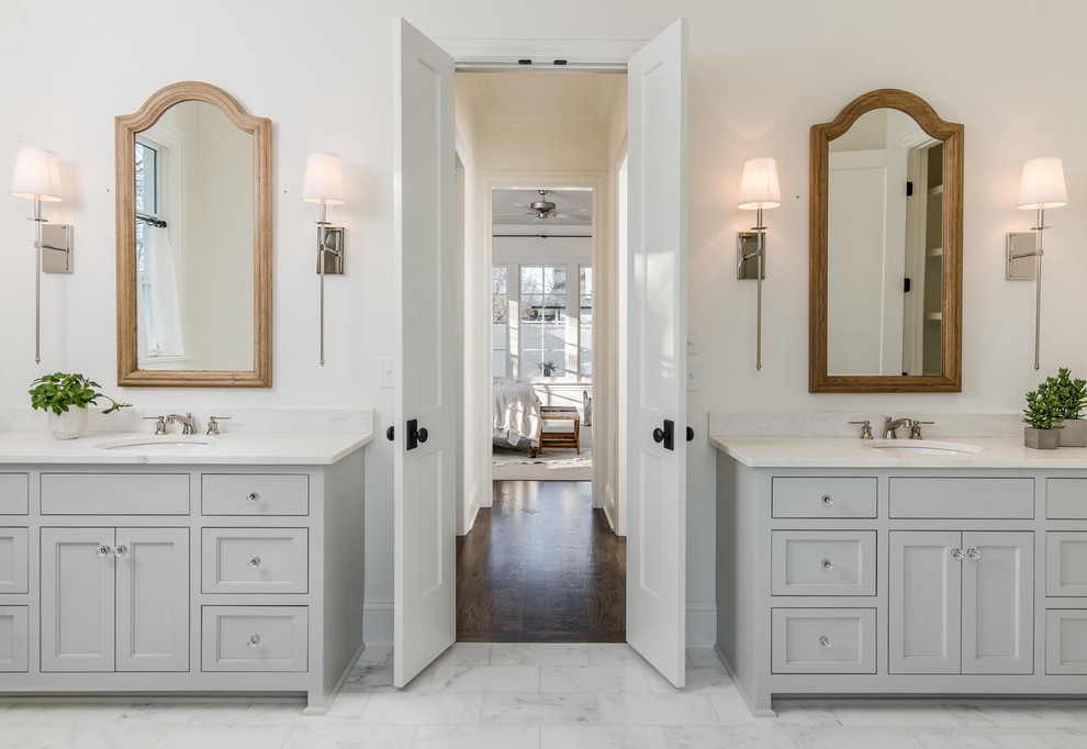 Inspiration pour une salle de bain traditionnelle avec un placard à porte shaker, des portes de placard grises, un mur blanc, un lavabo encastré et un sol blanc.