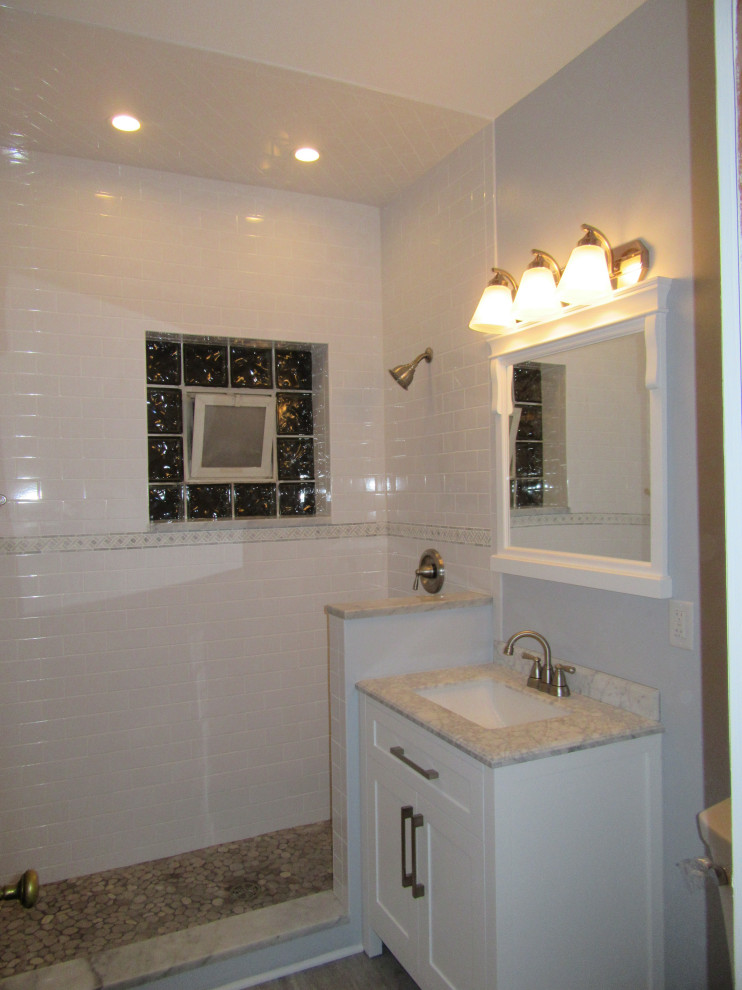 Design ideas for a small contemporary bathroom in Chicago with recessed-panel cabinets, white cabinets, an alcove shower, a two-piece toilet, grey tiles, ceramic tiles, blue walls, ceramic flooring, a submerged sink, granite worktops, grey floors, a hinged door and grey worktops.