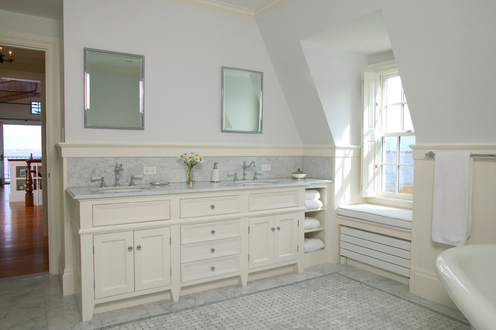 Cette photo montre une grande salle de bain principale avec un placard avec porte à panneau encastré, des portes de placard blanches, une baignoire sur pieds, un carrelage gris, un carrelage de pierre, un mur blanc, un sol en marbre, un lavabo encastré et un plan de toilette en marbre.
