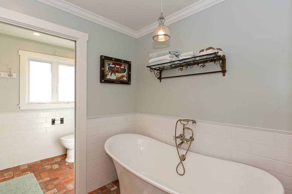 Cette image montre une grande douche en alcôve principale traditionnelle avec un placard à porte affleurante, des portes de placard grises, une baignoire indépendante, WC à poser, un carrelage blanc, des carreaux de céramique, un mur gris, un sol en brique, une vasque, un plan de toilette en marbre, un sol rouge, une cabine de douche à porte battante et un plan de toilette gris.