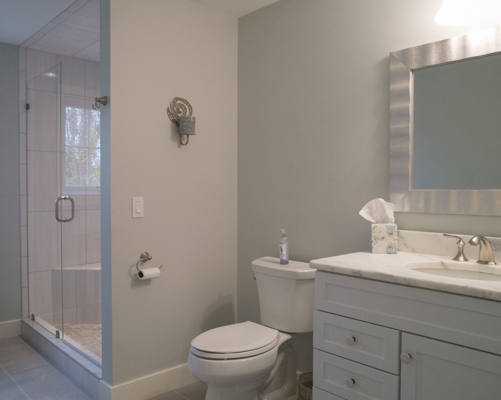 Mid-sized beach style 3/4 gray tile and ceramic tile ceramic tile alcove shower photo in Providence with recessed-panel cabinets, white cabinets, a one-piece toilet, blue walls and granite countertops