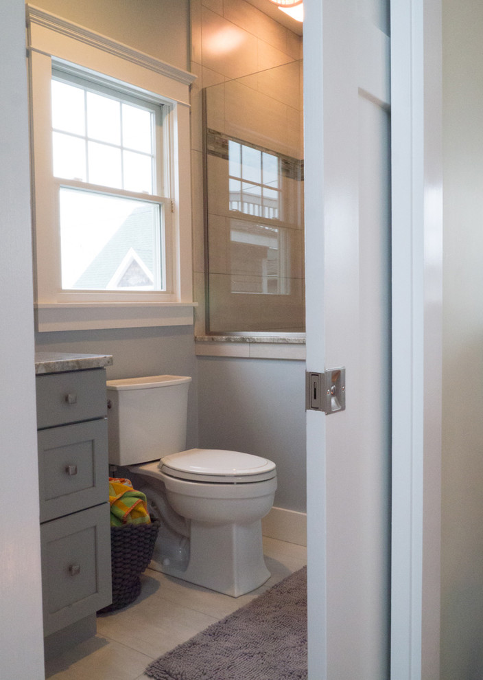 Photo of a small coastal bathroom in Providence with recessed-panel cabinets, grey cabinets, an alcove shower, a one-piece toilet, grey tiles, ceramic tiles, grey walls, ceramic flooring, an integrated sink and granite worktops.