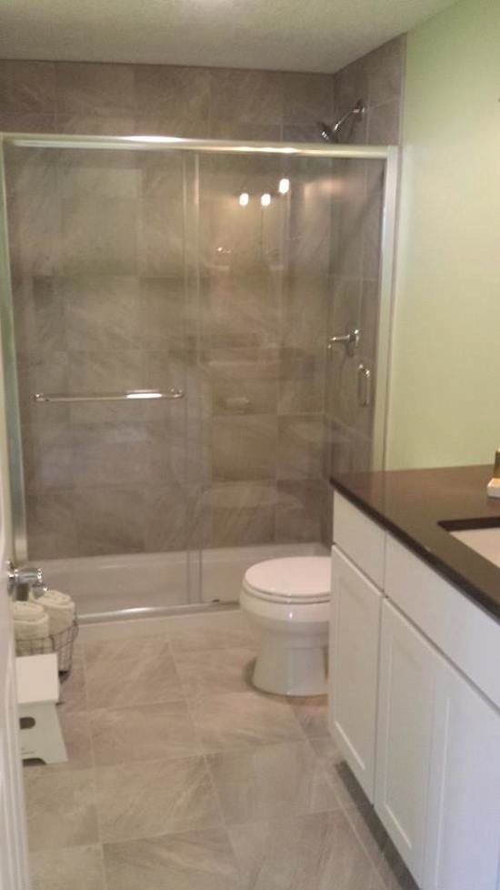 Exempel på ett mellanstort klassiskt badrum med dusch, med ett undermonterad handfat, luckor med infälld panel, vita skåp, bänkskiva i akrylsten, en kantlös dusch, grå kakel, stenkakel, gröna väggar och linoleumgolv