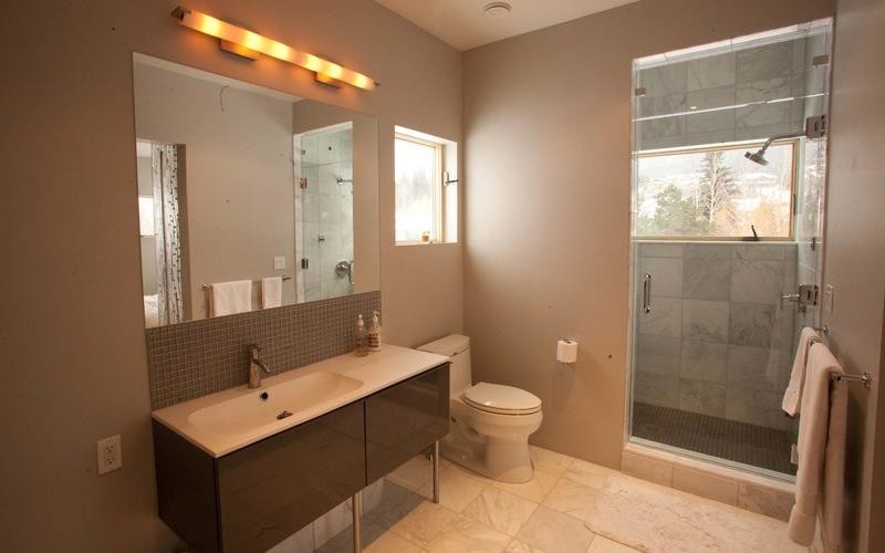 Photo of a large contemporary ensuite bathroom in Other with an alcove shower, beige walls, flat-panel cabinets, brown cabinets, a two-piece toilet, grey tiles, stone tiles, marble flooring, an integrated sink and engineered stone worktops.