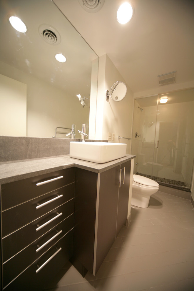 Foto på ett mellanstort funkis badrum med dusch, med släta luckor, svarta skåp, en dusch i en alkov, en toalettstol med separat cisternkåpa, grå kakel, keramikplattor, vita väggar, klinkergolv i småsten, ett fristående handfat och granitbänkskiva