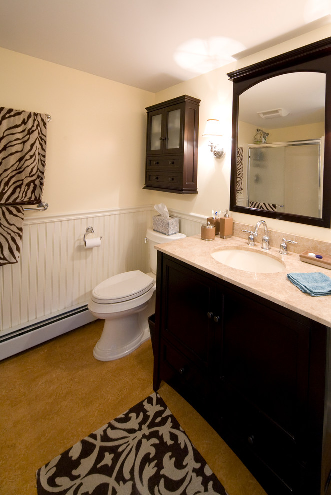 Foto på ett vintage badrum, med släta luckor, svarta skåp, ett badkar i en alkov, en dusch/badkar-kombination, en toalettstol med separat cisternkåpa, gula väggar, linoleumgolv, ett undermonterad handfat och bänkskiva i akrylsten