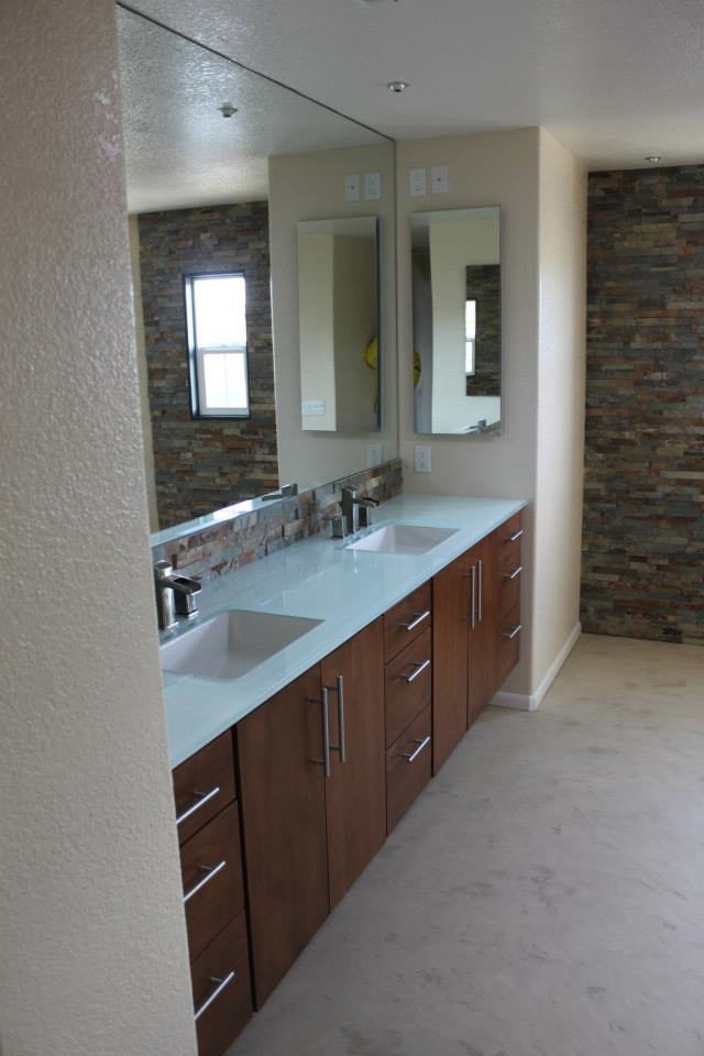 Bathroom - stone tile bathroom idea in San Diego with medium tone wood cabinets and glass countertops