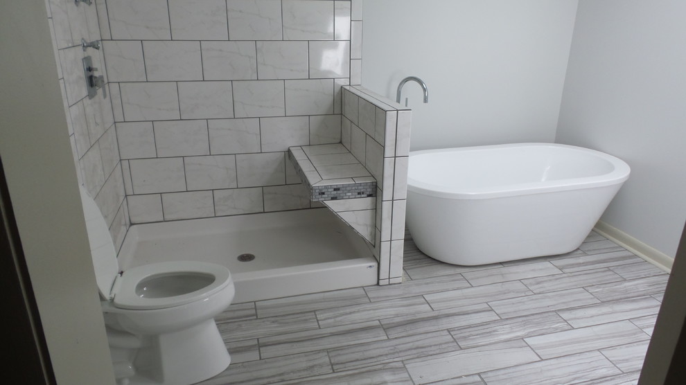 На фото: большая главная ванная комната в современном стиле с отдельно стоящей ванной, открытым душем, раздельным унитазом, серой плиткой, керамогранитной плиткой, серыми стенами и полом из керамогранита