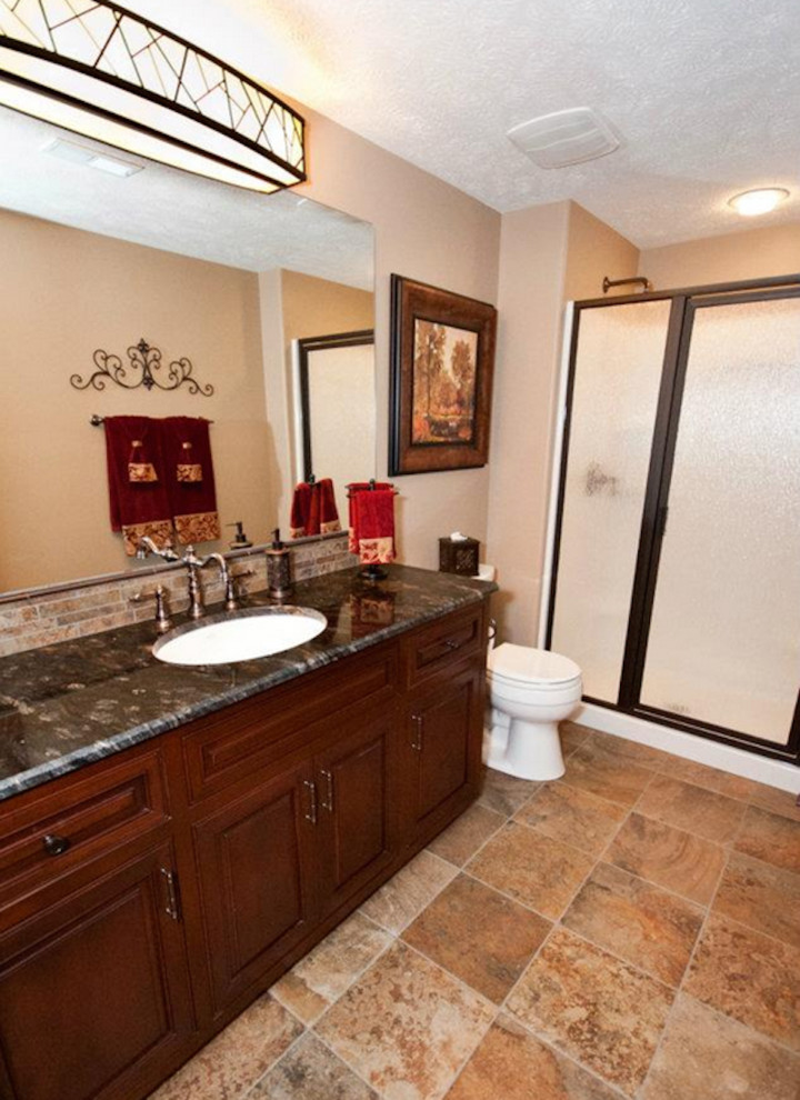Bild på ett vintage badrum, med ett undermonterad handfat, luckor med infälld panel, skåp i mörkt trä, bänkskiva i onyx, en kantlös dusch, en toalettstol med hel cisternkåpa, beige väggar och klinkergolv i porslin