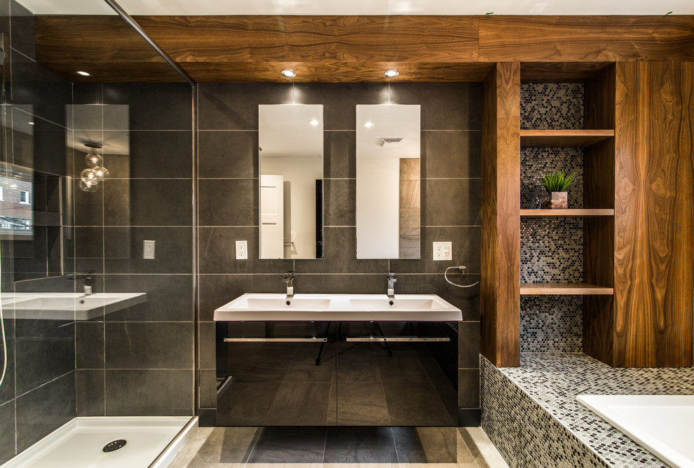 На фото: главная ванная комната среднего размера с плоскими фасадами, черными фасадами, столешницей из искусственного камня, накладной ванной, угловым душем, раздельным унитазом, серой плиткой, керамогранитной плиткой, серыми стенами и полом из керамогранита