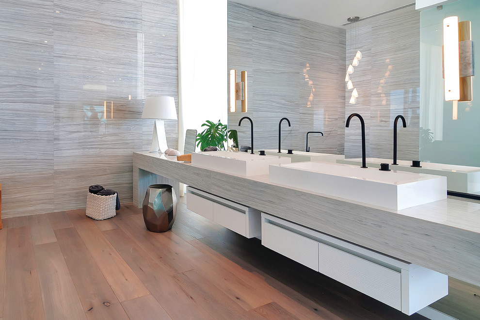 Идея дизайна: главная ванная комната в современном стиле с плоскими фасадами, белыми фасадами, серой плиткой, серыми стенами, светлым паркетным полом, настольной раковиной и зеркалом с подсветкой