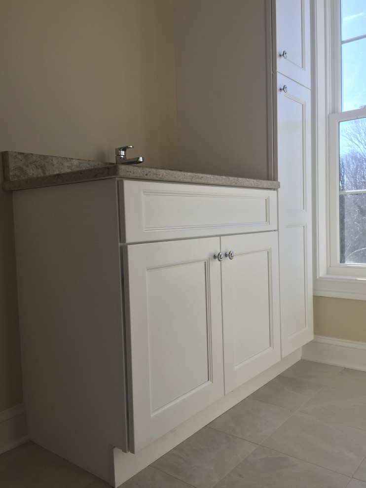 Klassisches Badezimmer mit Schrankfronten im Shaker-Stil, weißen Schränken, grauen Fliesen, beiger Wandfarbe und Granit-Waschbecken/Waschtisch in New York
