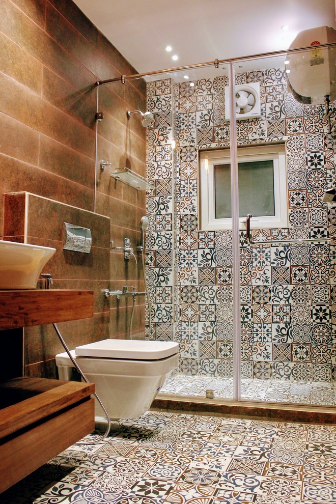 Alcove shower - mid-sized eclectic multicolored tile and cement tile cement tile floor alcove shower idea in Delhi with furniture-like cabinets, medium tone wood cabinets, a wall-mount toilet, beige walls, a console sink, wood countertops and a hinged shower door