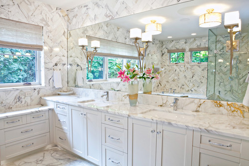 Bathroom Cabinets – white shaker double vanity with marble countertop, full-height marble wall tile, large mirror, and chrome hardware.