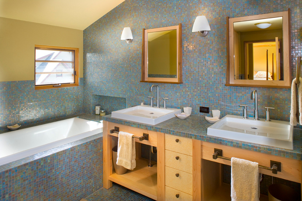 Diseño de cuarto de baño principal moderno de tamaño medio con armarios abiertos, puertas de armario de madera clara, bañera encastrada, baldosas y/o azulejos azules, baldosas y/o azulejos de cerámica, paredes amarillas, suelo de baldosas de cerámica, lavabo integrado y encimera de azulejos
