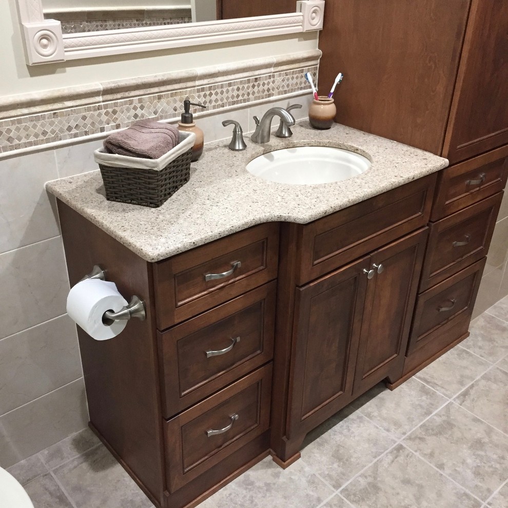 Photo of a medium sized traditional ensuite bathroom in New York with dark wood cabinets, a one-piece toilet, grey tiles, white tiles, stone slabs, white walls, ceramic flooring, soapstone worktops, recessed-panel cabinets, a submerged sink and grey floors.