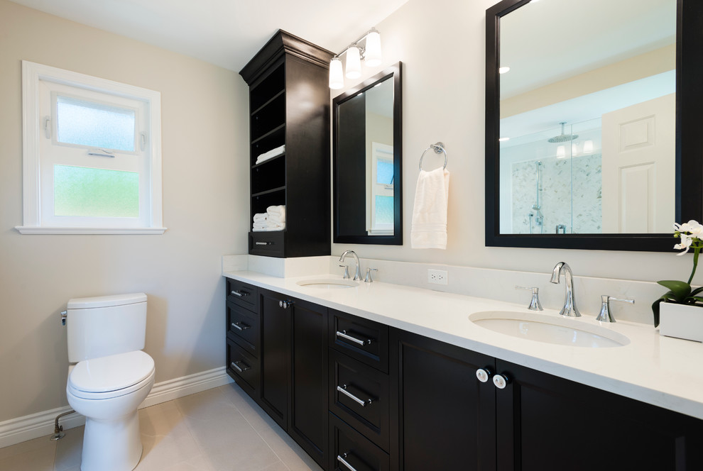 Klassisk inredning av ett mellanstort en-suite badrum, med skåp i shakerstil, svarta skåp, en dusch i en alkov, en toalettstol med separat cisternkåpa, beige väggar, travertin golv, ett undermonterad handfat och bänkskiva i akrylsten