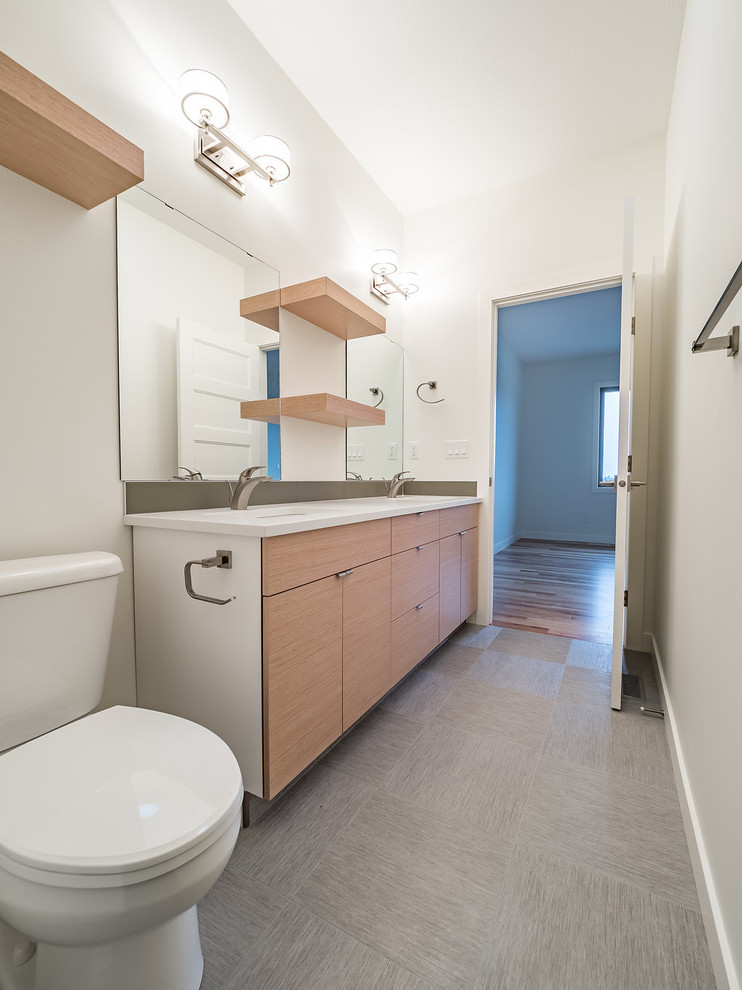 Mid-sized danish master green tile and porcelain tile vinyl floor and gray floor bathroom photo in Edmonton with flat-panel cabinets, medium tone wood cabinets, a two-piece toilet, white walls, a drop-in sink and quartzite countertops