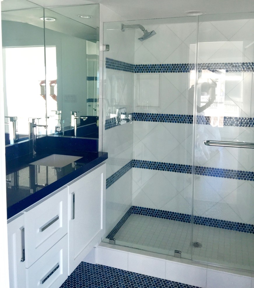 Example of a mid-sized transitional master gray tile and porcelain tile ceramic tile and blue floor doorless shower design in Houston with shaker cabinets, white cabinets, a one-piece toilet, white walls, a drop-in sink, solid surface countertops and a hinged shower door