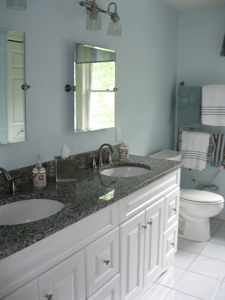 This is an example of a medium sized bohemian bathroom in Boston with recessed-panel cabinets, white cabinets, laminate worktops, white tiles, porcelain tiles, blue walls, porcelain flooring and a two-piece toilet.