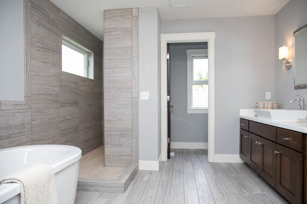 This is an example of a contemporary ensuite bathroom in Minneapolis with a vessel sink, recessed-panel cabinets, dark wood cabinets, marble worktops, a freestanding bath, a walk-in shower, a two-piece toilet, grey tiles, ceramic tiles and grey walls.