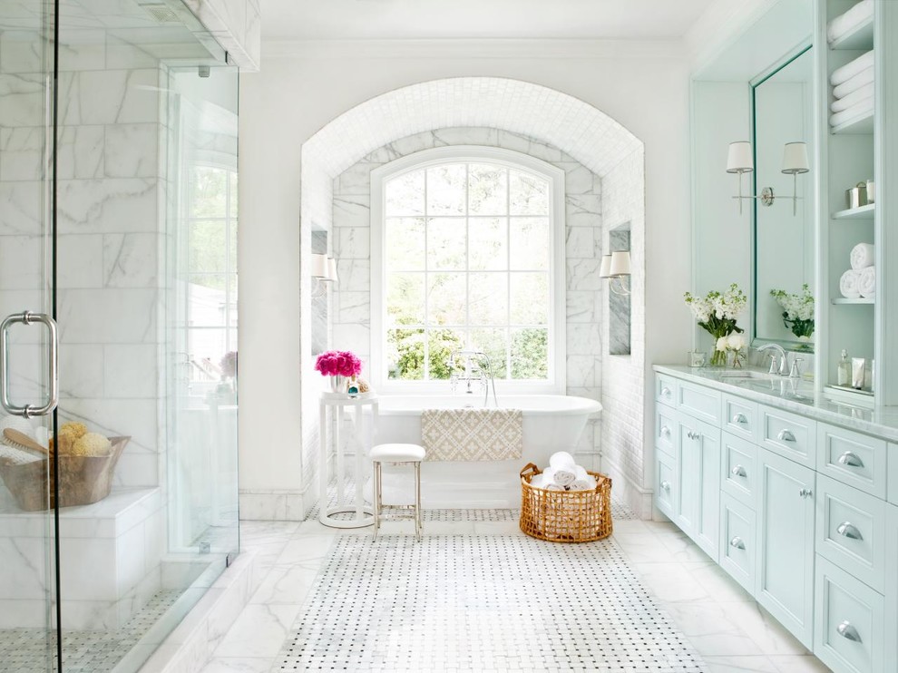 Cette image montre une salle de bain principale victorienne avec un lavabo encastré, une baignoire indépendante, un carrelage blanc, un carrelage de pierre, un sol en marbre, un placard à porte affleurante et un mur blanc.