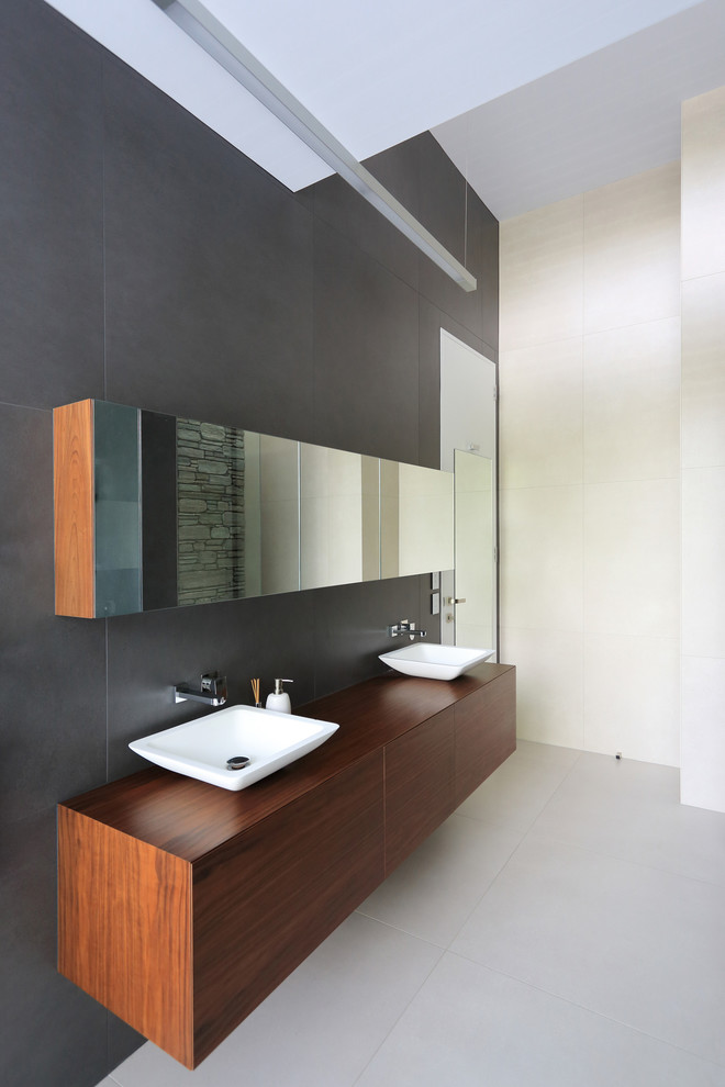 Cette image montre une salle de bain principale design en bois foncé avec un placard en trompe-l'oeil, un carrelage gris, des carreaux de porcelaine, un sol en carrelage de porcelaine, une vasque et un plan de toilette en bois.