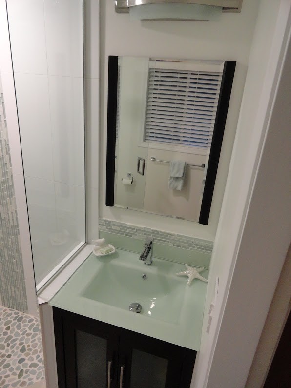 Modern inredning av ett mellanstort en-suite badrum, med luckor med glaspanel, skåp i mörkt trä, en hörndusch, grå kakel, vit kakel, porslinskakel, vita väggar och bänkskiva i glas