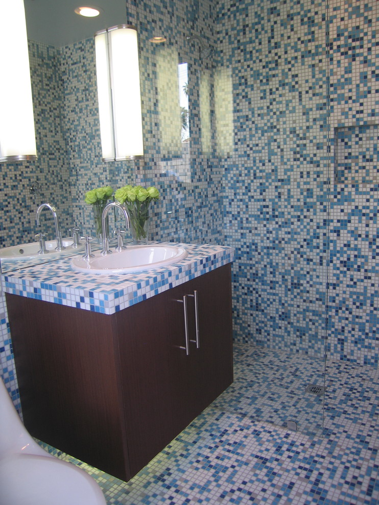Foto de cuarto de baño actual con lavabo encastrado, armarios con paneles lisos, puertas de armario de madera en tonos medios, encimera de azulejos, ducha abierta, sanitario de una pieza y baldosas y/o azulejos azules