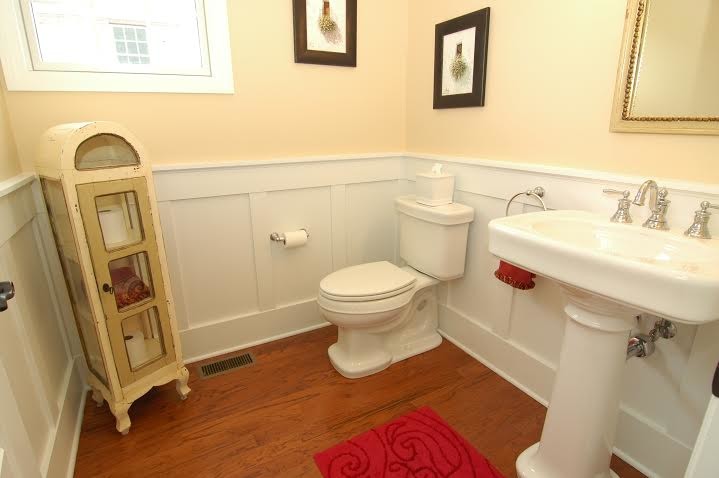 Mittelgroßes Klassisches Badezimmer mit Wandtoilette mit Spülkasten, beiger Wandfarbe, braunem Holzboden und Sockelwaschbecken in Sonstige