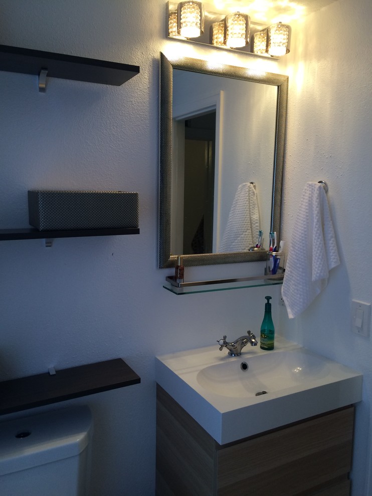 Immagine di una piccola stanza da bagno con doccia moderna con ante lisce, ante in legno chiaro, WC a due pezzi, pareti bianche, lavabo a consolle e top in superficie solida