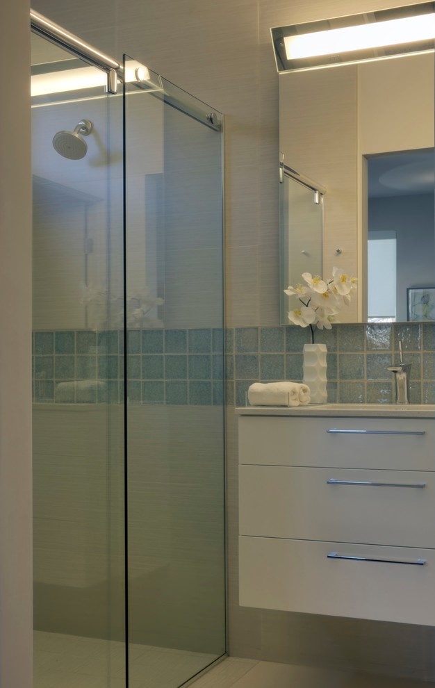Cette photo montre une douche en alcôve principale tendance avec un placard à porte plane, des portes de placard blanches, WC à poser, un carrelage bleu, un carrelage blanc, des carreaux de céramique, un mur blanc, un lavabo encastré et un plan de toilette en quartz modifié.