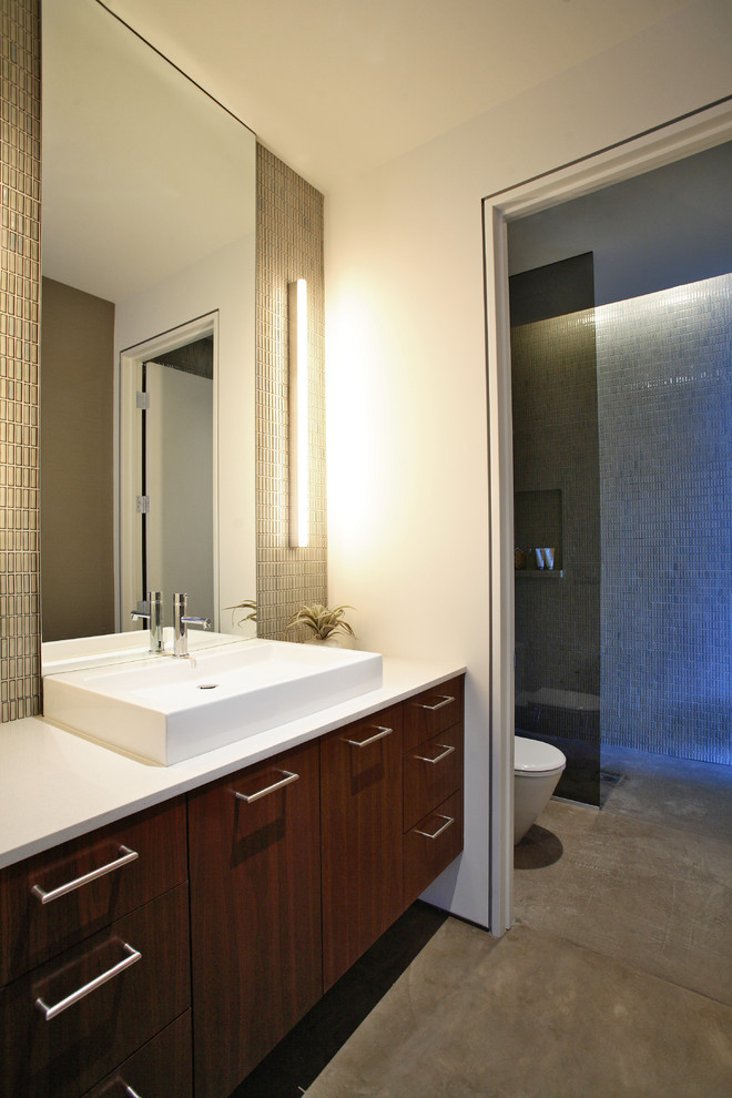 Example of a large trendy 3/4 green tile and ceramic tile concrete floor doorless shower design in Los Angeles with flat-panel cabinets, dark wood cabinets, a one-piece toilet, white walls, a vessel sink and quartz countertops