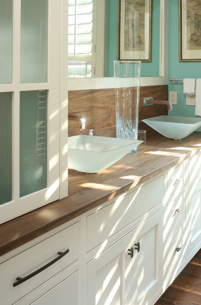 Ejemplo de cuarto de baño principal contemporáneo de tamaño medio con lavabo sobreencimera, armarios con paneles lisos, puertas de armario blancas, encimera de madera, paredes azules y suelo de madera en tonos medios